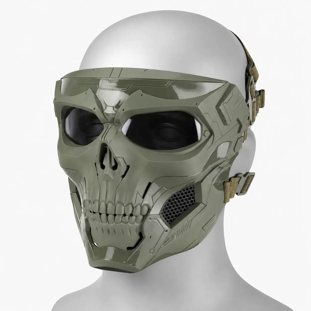 A tactical full-face mask with a skull-inspired design, displayed on a white mannequin head. The mask is olive green with black visor and eye areas, and has tan adjustment straps on the sides.
